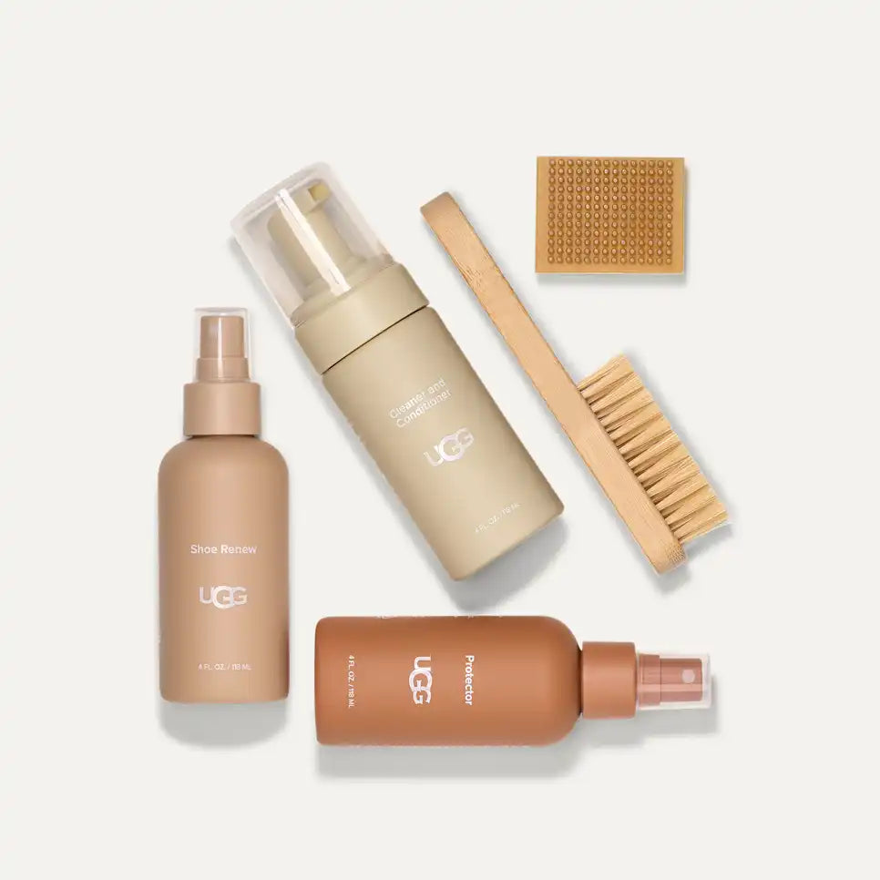 Set of UGG shoe care products including bottles and a brush on a white background
