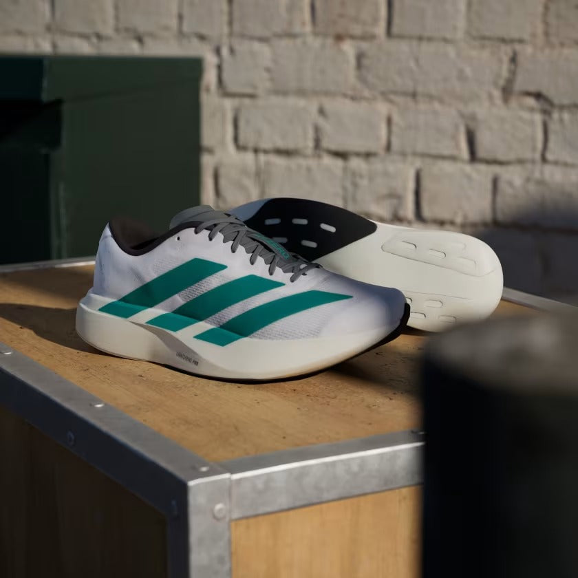 White and green athletic shoes on a wooden box with a brick wall background