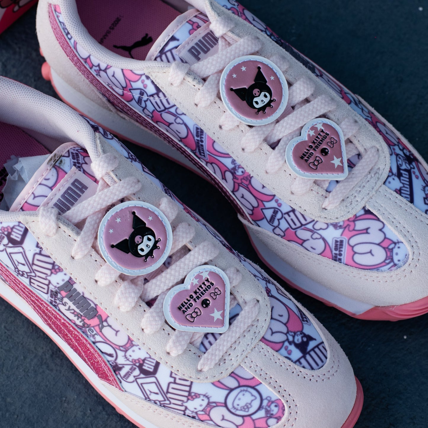 Pair of pink and white sneakers with cartoon character designs on a dark surface
