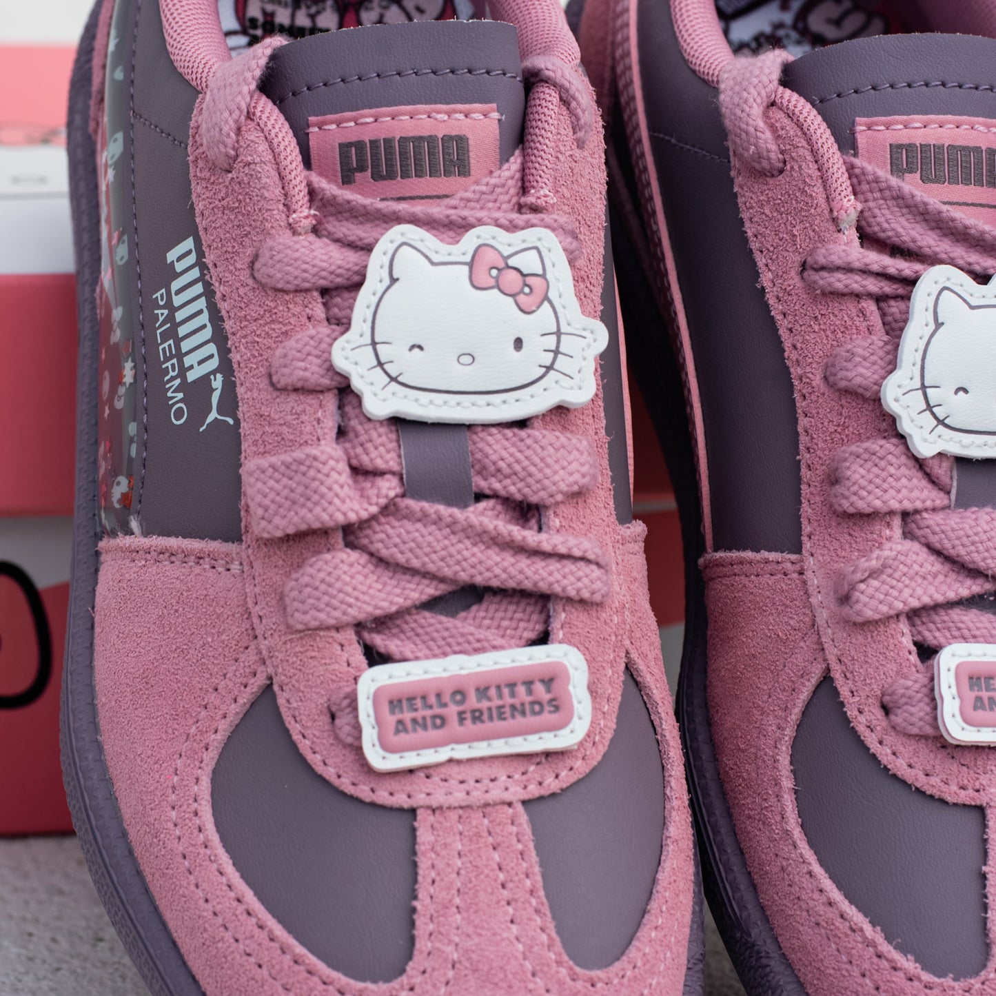 Pink and purple sneakers with Hello Kitty design on a light gray surface.