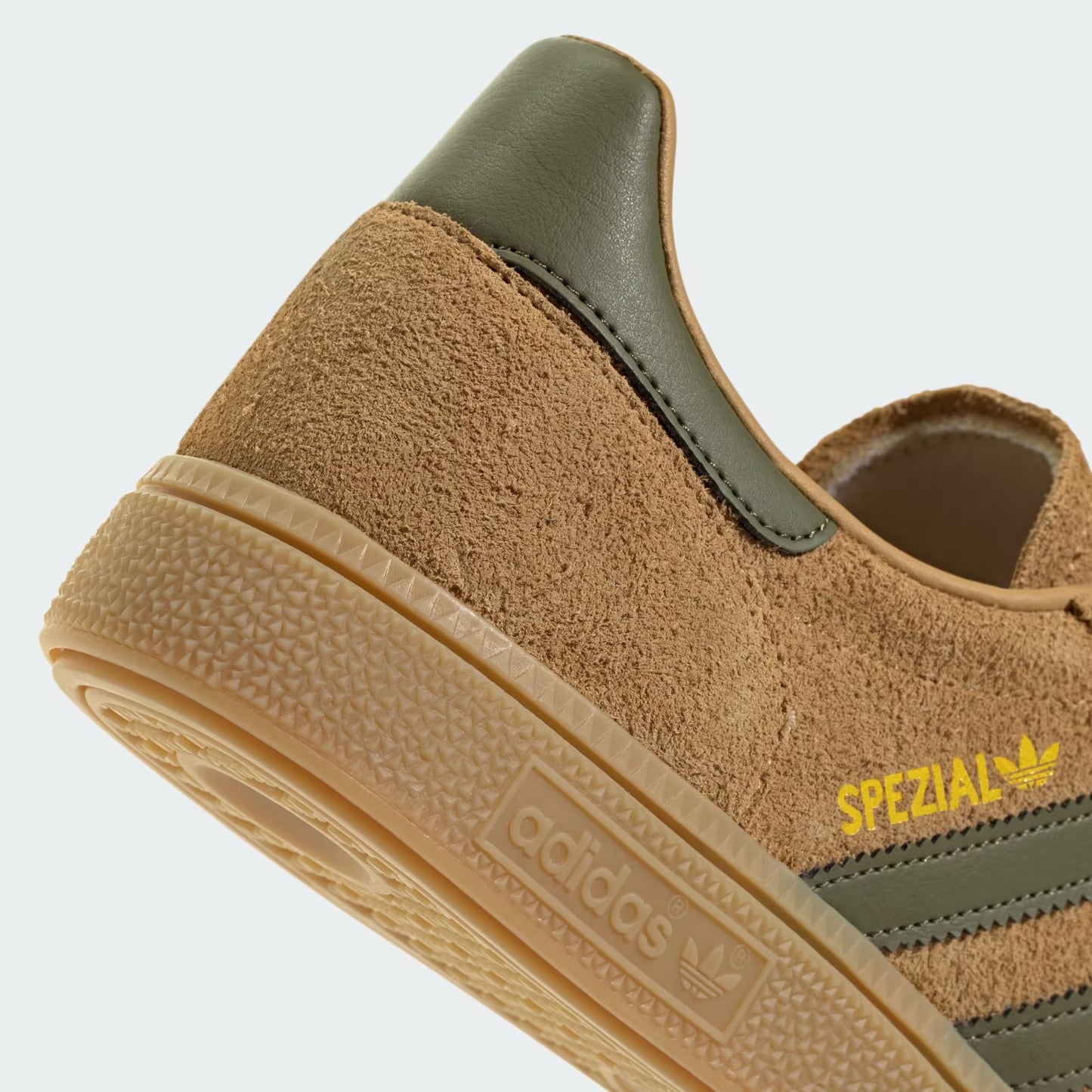 Brown Adidas sneaker with green accents on a light gray background