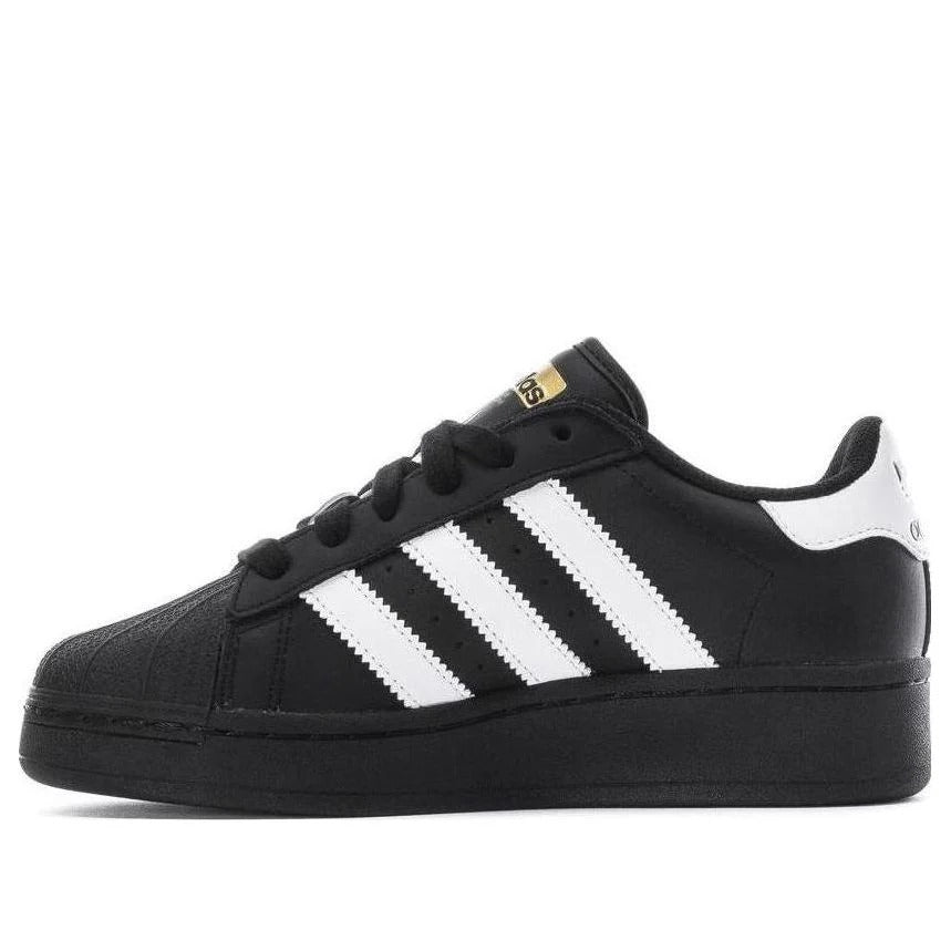Black Adidas sneaker with white stripes on a white background