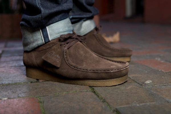 Brown suede shoes on a person walking on a brick pavement