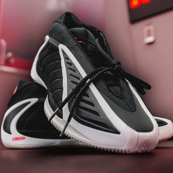 Black and white sneakers AE2_lucid_red on a red surface with a blurred background