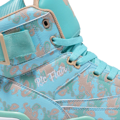 A close-up of a high-top sneaker in light turquoise blue with a beige and brown paisley pattern, featuring a hook-and-loop strap on the side and the text 'Ric Flair' printed on the side panel.