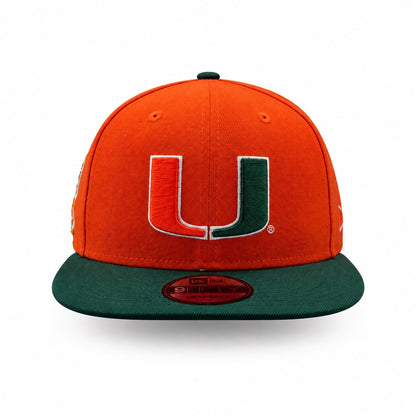An orange and green Miami Hurricanes New Era 9FIFTY fitted cap with a large embroidered 'U' logo on the front, set against a plain white background.