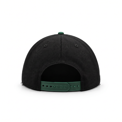 The back view of a black snapback cap with a contrasting green adjustable strap and green button on a white background.