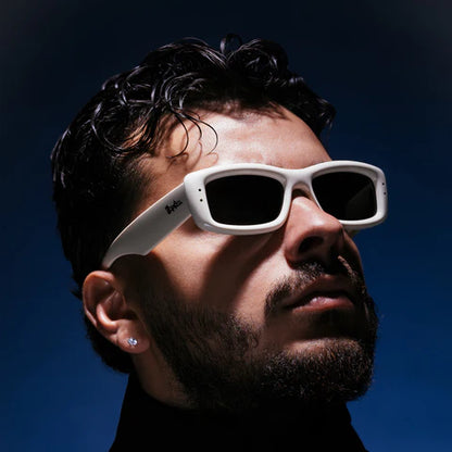 Man wearing white sunglasses against a dark background