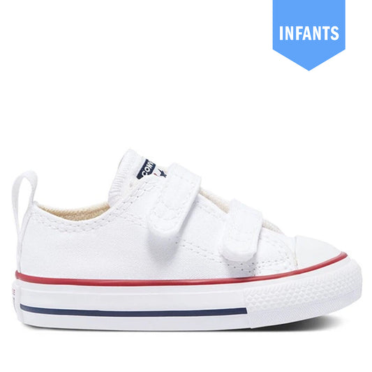 A white canvas low-top sneaker for toddlers, featuring two hook-and-loop straps, a red stripe, and a navy blue stripe on the white rubber sole. A blue 'INFANTS' badge is in the top right corner.