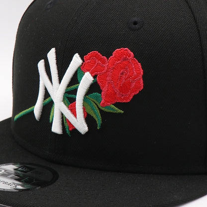Black cap with embroidered design of roses and letters on a white background