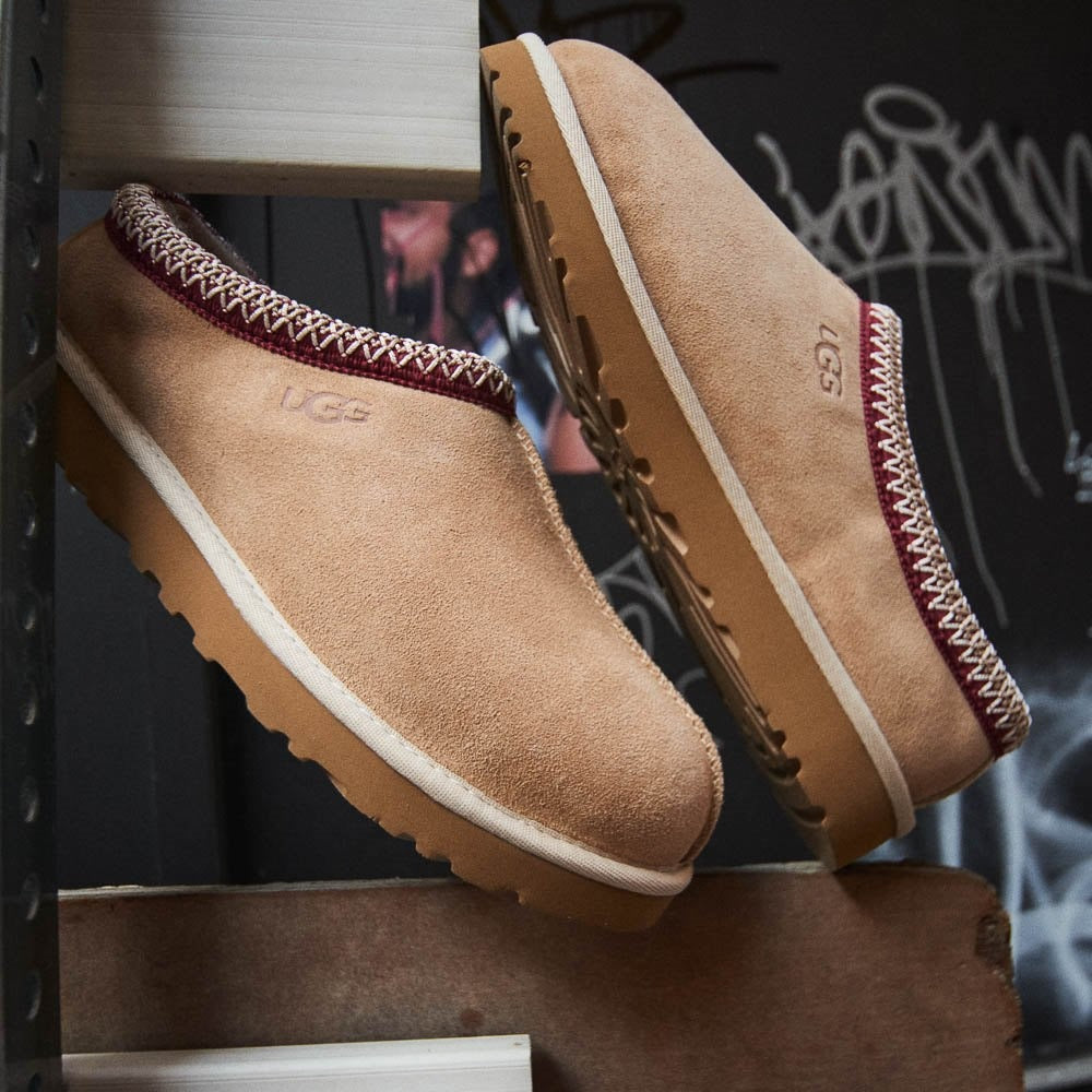 Tan UGG slippers on a dark background